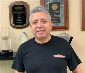 Photo of employee in front of a wall of awards