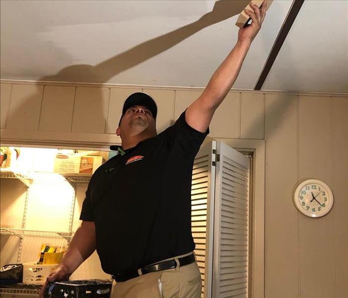 A SERVPRO technician standing on a ladder